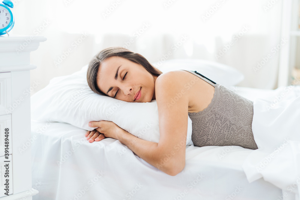 Portrait of a young woman sleeping in cozy light colored bedroom lying in the bed with eyes closed Portrait of a young woman sleeping in cozy light colored bedroom lying in the bed with eyes closed