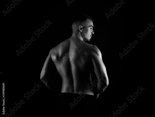 Muscular male torso of fit bodybuilder on black background in black and white
