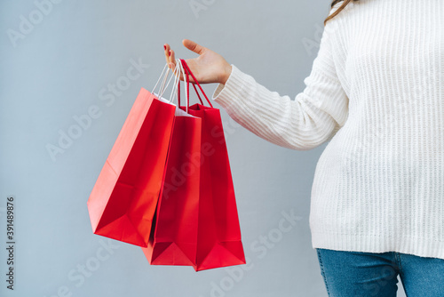 Cropped shot of female hand with bunch of red and white paper shopping bags