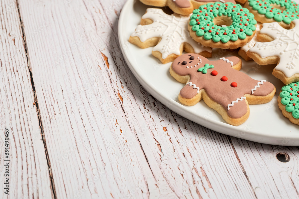 Christmas cookies and gingerbread man cookies with icing and decorations on a white weathered wooden table background with copy space and room for text.