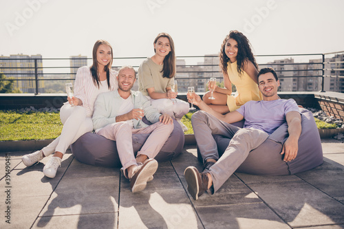 Photo of good mood smiling happy cheerful positive group of friends sit armchair drink champagne outside on rooftop