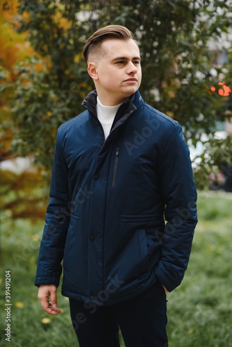 Portrait of a young handsome man, model of fashion, with modern hairstyle in urban background, wearing casual clothes.