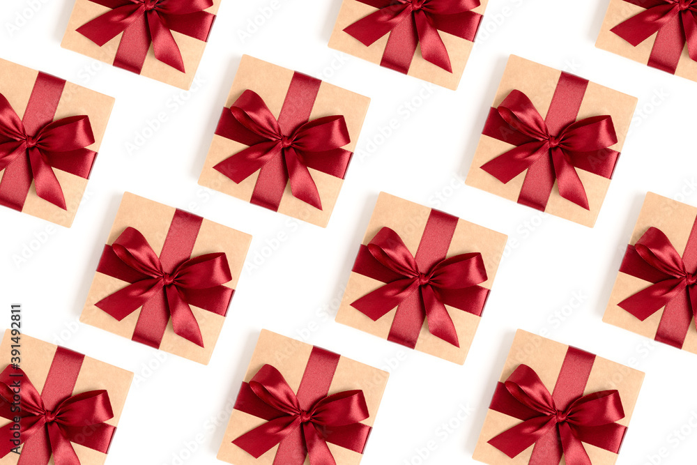 Repetitive pattern made of gift boxes tied with red ribbons on a white background. Holdays backdrop. Repetitive pattern made of gift boxes tied with red ribbons on a white background. Holdays backdrop.