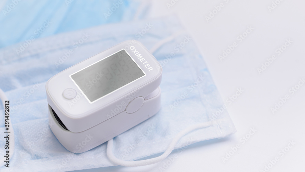 Portable Pulse Oximeter on Background face mask to monitor oxygen level at home. Covid-19, healthcare concept. Copy space. Pulse Rate Health Testor Oximeter is used to measure air in lungs. Portable Pulse Oximeter on Background face mask to monitor oxygen level at home. Covid-19, healthcare concept. Copy space. Pulse Rate Health Testor Oximeter is used to measure air in lungs.