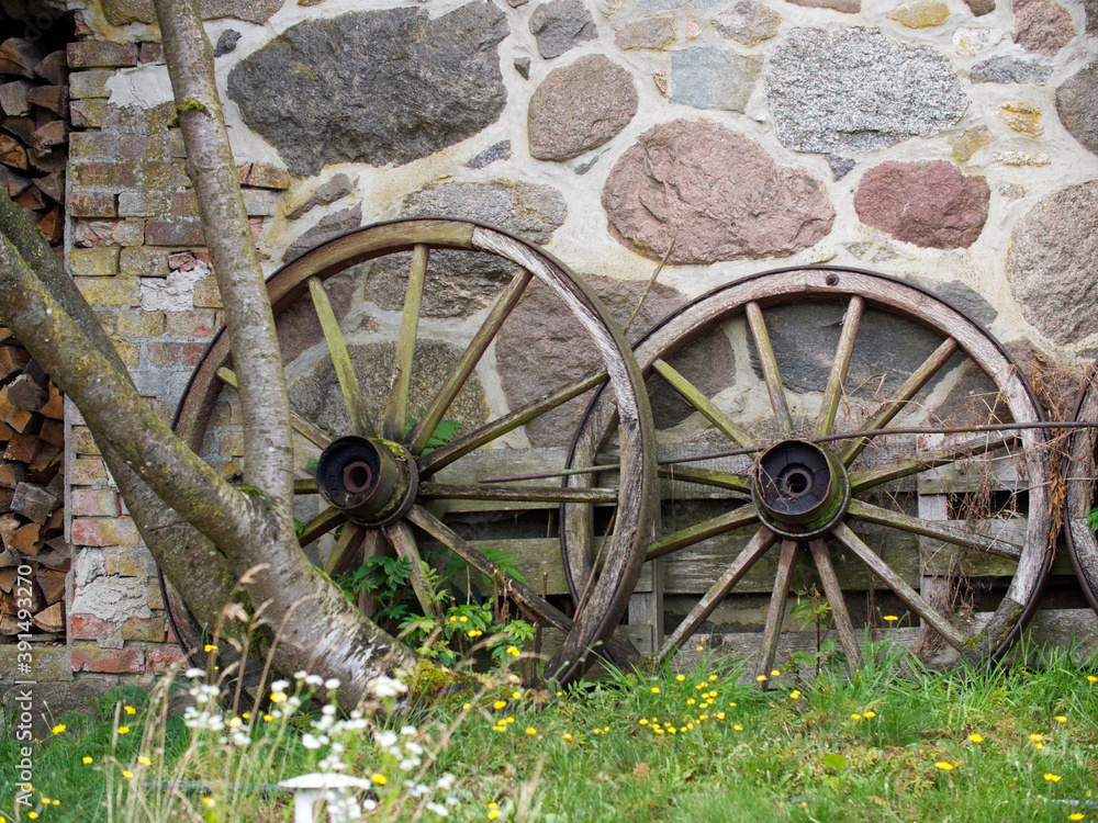 Old wooden weathered wooden wheels at a natural stone wall.