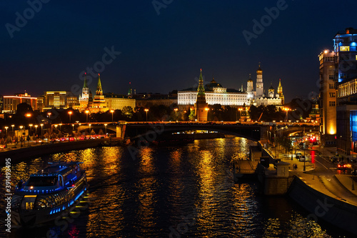 View of the Kremlin and the Moskva River from the Patriarchal Bridge at night, river tram illuminated by lights © Shauerman