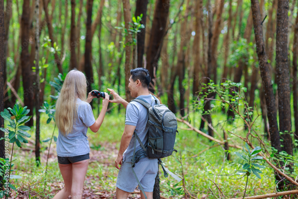 Young couple hiking trough forest and watching birds with binoculars. Young couple hiking trough forest and watching birds with binoculars.