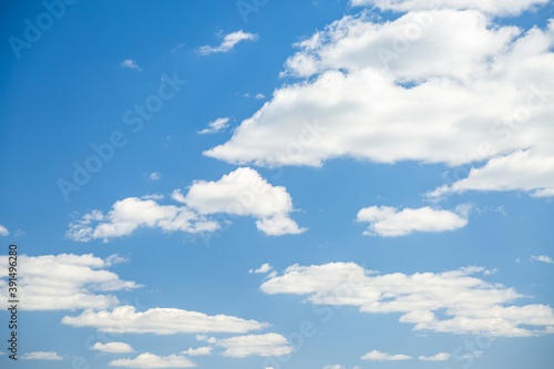 Blue sky background with white fluffy clouds in the fresh sunny day.