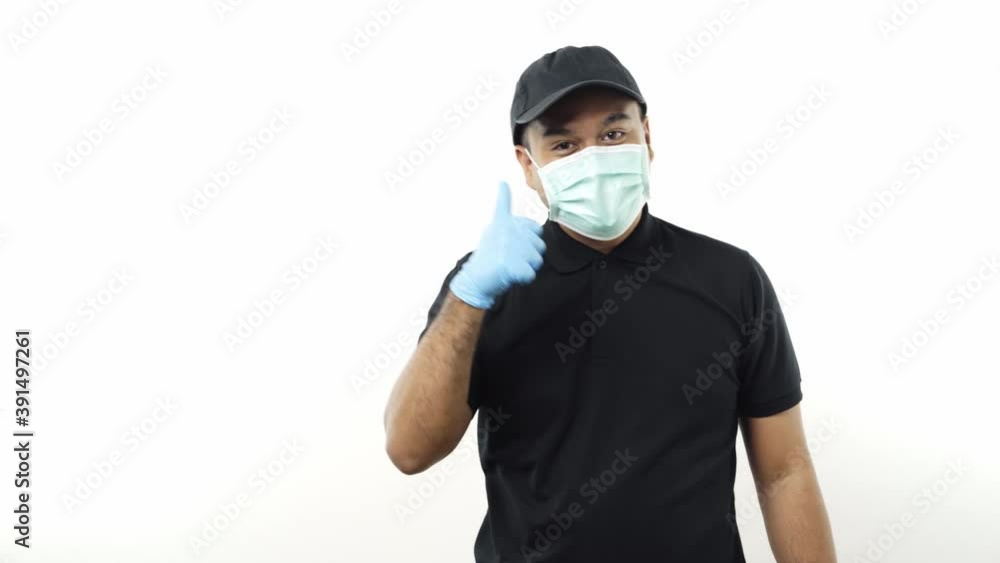 Young asian delivery man in black uniform wearing protection mask and medical rubber gloves pointing the finger to blank space for text on isolated white background. 4k Resolution. Young asian delivery man in black uniform wearing protection mask and medical rubber gloves pointing the finger to blank space for text on isolated white background. 4k Resolution.