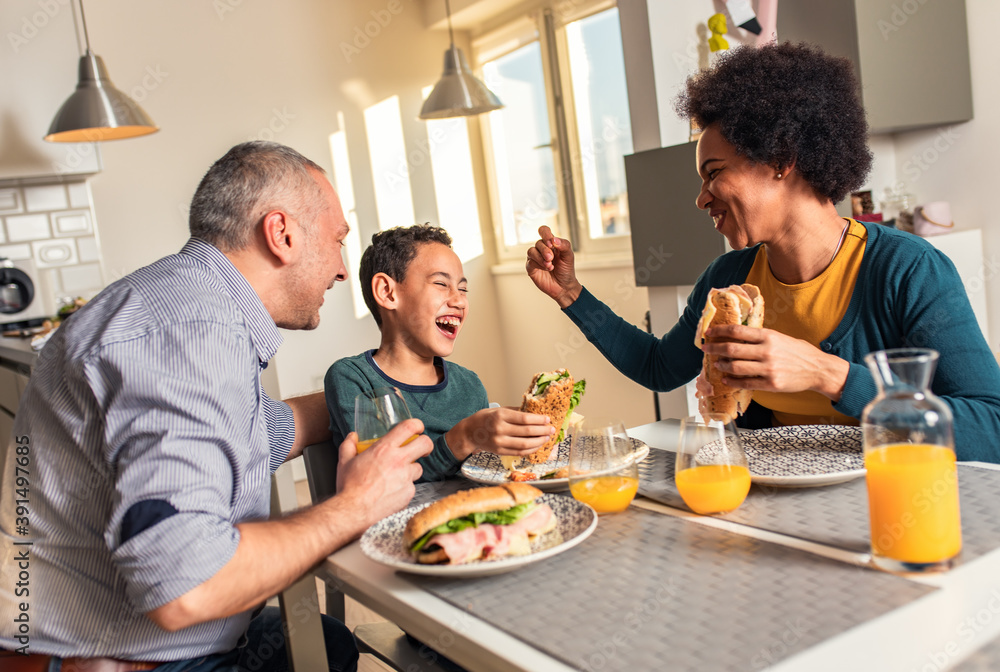 Smiling mixed race family sitting at the kitchen table having breakfast at home. Smiling mixed race family sitting at the kitchen table having breakfast at home.