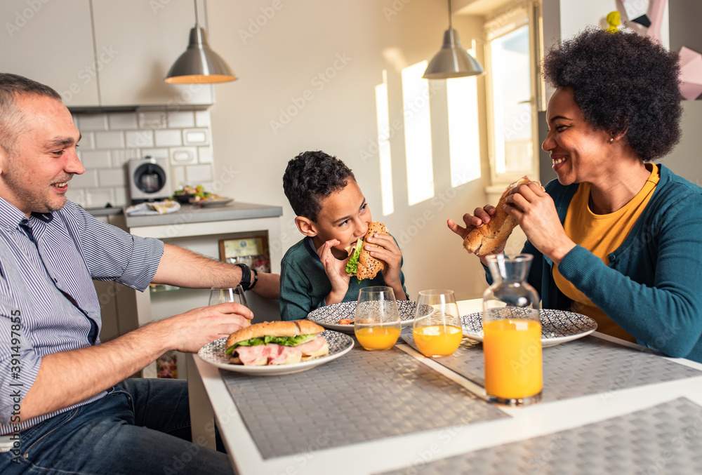 Smiling mixed race family sitting at the kitchen table having breakfast at home. Smiling mixed race family sitting at the kitchen table having breakfast at home.