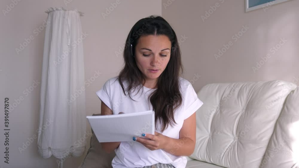 Young business woman wears headset talks to web camera making distance online video conference call. Female internet teacher doing distant chat working from home. Webcam view Young business woman wears headset talks to web camera making distance online video conference call. Female internet teacher doing distant chat working from home. Webcam view