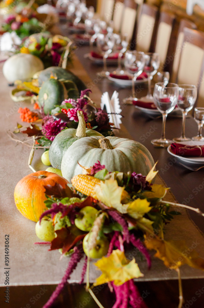 Creative layout with ripe orange pumpkins, fallen leaves, dry flowers on rustic wooden table