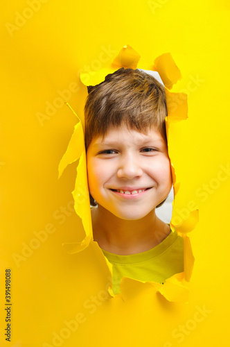 happy child looks into the camera lens on a yellow background. photo
