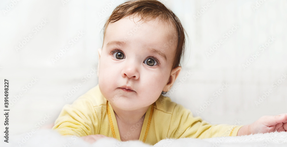 Cute funny little child lying on bed on white background. little baby girl learning to crawl and playing in bedroom. Cute funny little child lying on bed on white background. little baby girl learning to crawl and playing in bedroom.