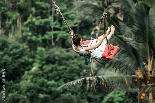Young woman swing in the jungle of Bali island. Rainforest of Indonesia. Travel concept.