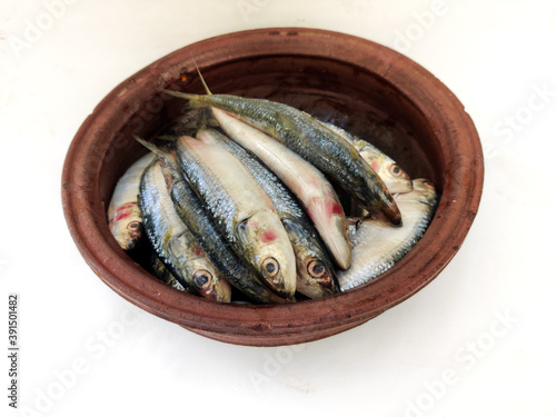 Close up view of Fresh Indian oil sardine on a Sand pot,White Background.