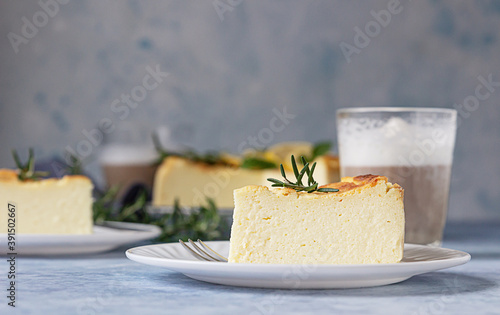 Lemon vanilla cheesecake decorated with rosemary, mint and lemon slices. Ricotta no crust cheesecake or casserole. Blue concrete background.