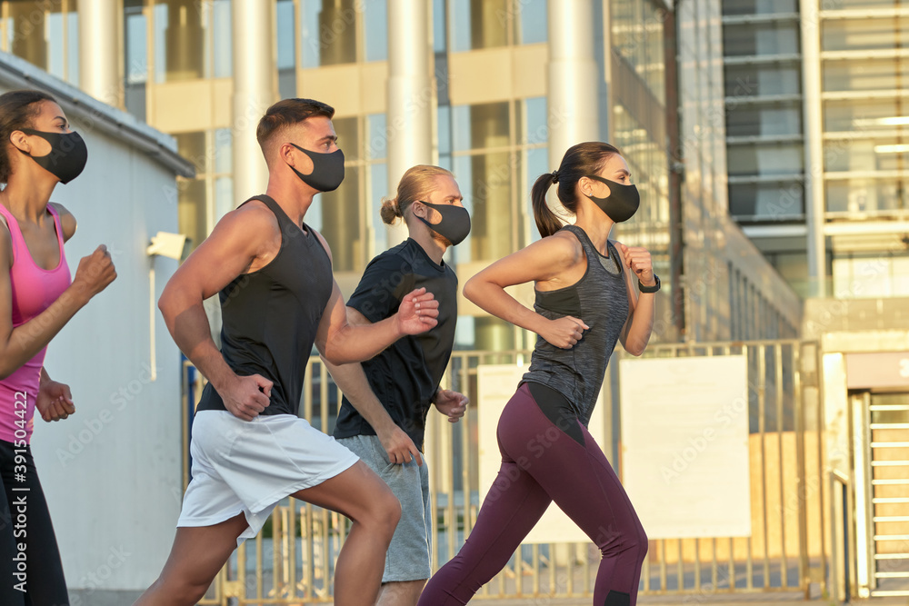 Young mixed race team in protective masks training outdoors