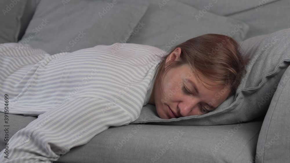 Exhausted or bored young sleepy woman falls down on sofa. Lazy housewife falls on the sofa with pillows and falls asleep Exhausted or bored young sleepy woman falls down on sofa. Lazy housewife falls on the sofa with pillows and falls asleep