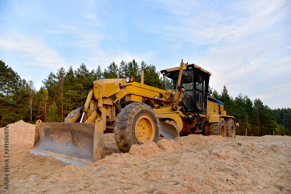 Motor Grader on road construction in forest area. Greyder leveling the sand, ground and gravel during road work. Heavy machinery and construction equipment for grading. Earthworks grader machine Motor Grader on road construction in forest area. Greyder leveling the sand, ground and gravel during road work. Heavy machinery and construction equipment for grading. Earthworks grader machine
