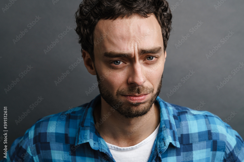 Obraz premium Unshaven unhappy guy posing and looking at camera
