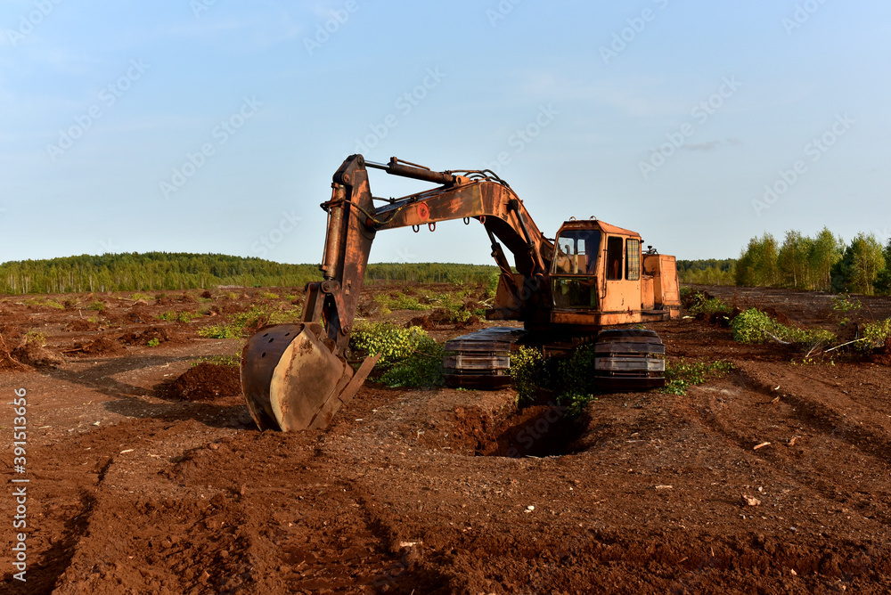 Foto de Excavator digging drainage ditch in peat extraction site