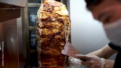 A cook cuts meat to make shawarma, gyros, doner kebab.