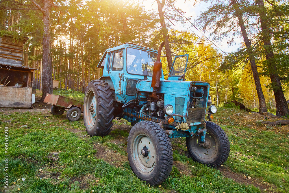 An old blue tractor stands in a farmyard An old blue tractor stands in a farmyard