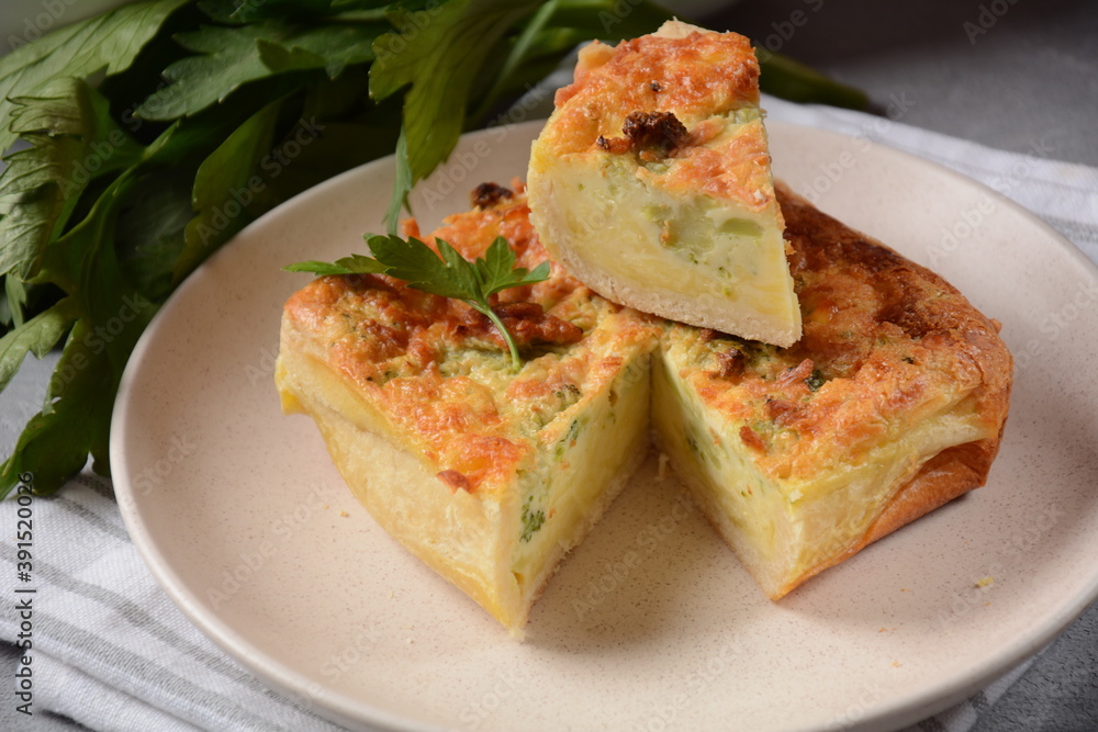 Homemade quiche or pie with broccoli, seasonings, champignons and cheese on a gray background. Homemade quiche or pie with broccoli, seasonings, champignons and cheese on a gray background.