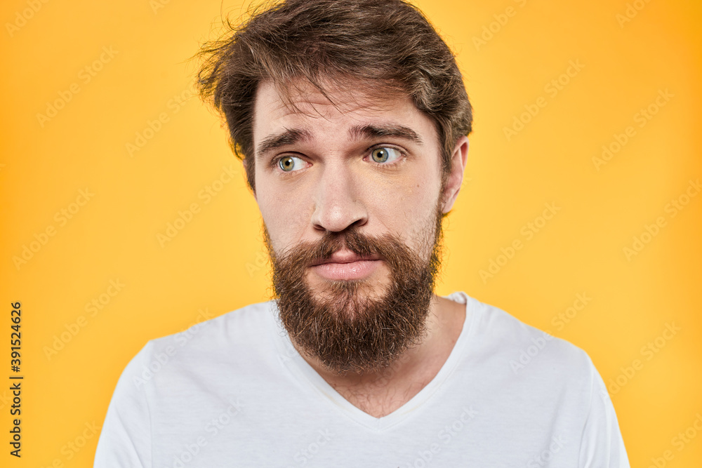 Obraz premium Man with emotional expression white t-shirt close-up studio yellow background