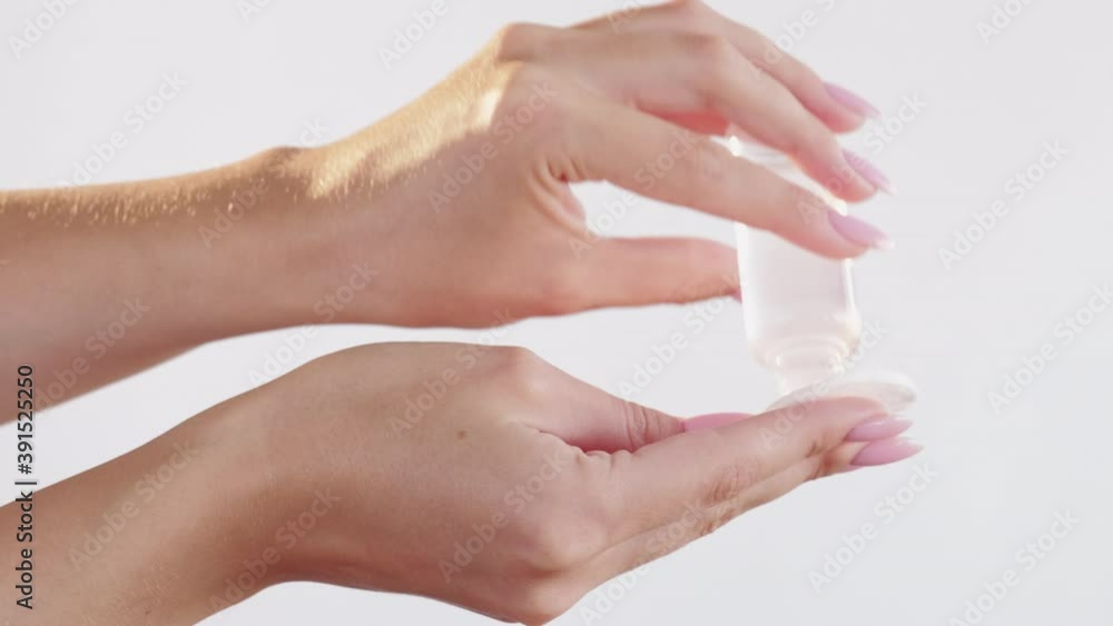 Skincare product. Face cleansing. Hygiene wellness. Makeup remover presentation. Woman hands pouring tonic from clear bottle on cotton pad isolated on light neutral background.