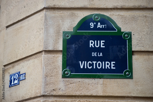 Closeup of Victory street name on the traditional parisian street plate on stoned building - (rue de la victoire in french)