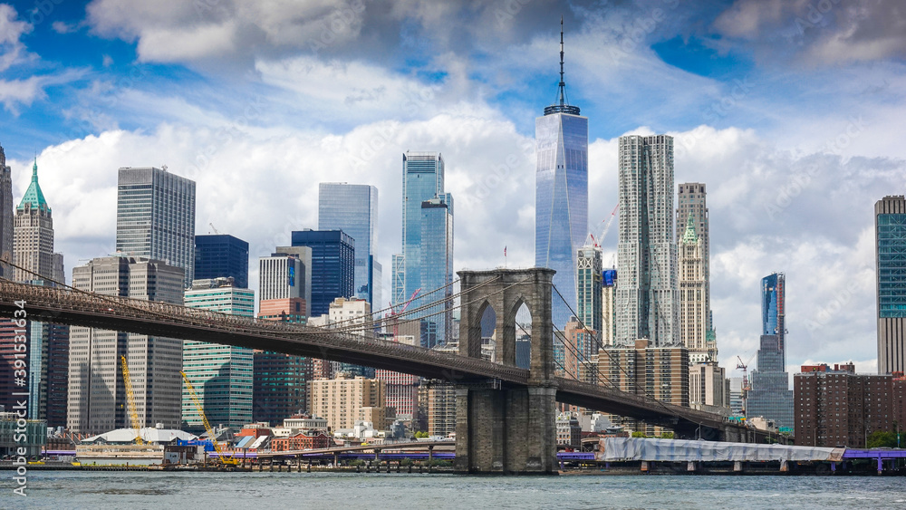 Obraz premium View from Brooklyn Bridge to Manhattan in New York during sunny day with blue sky and white clouds