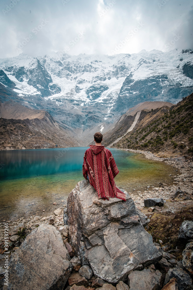 A young man with a poncho on vacation in Laguna Humantay, Peru