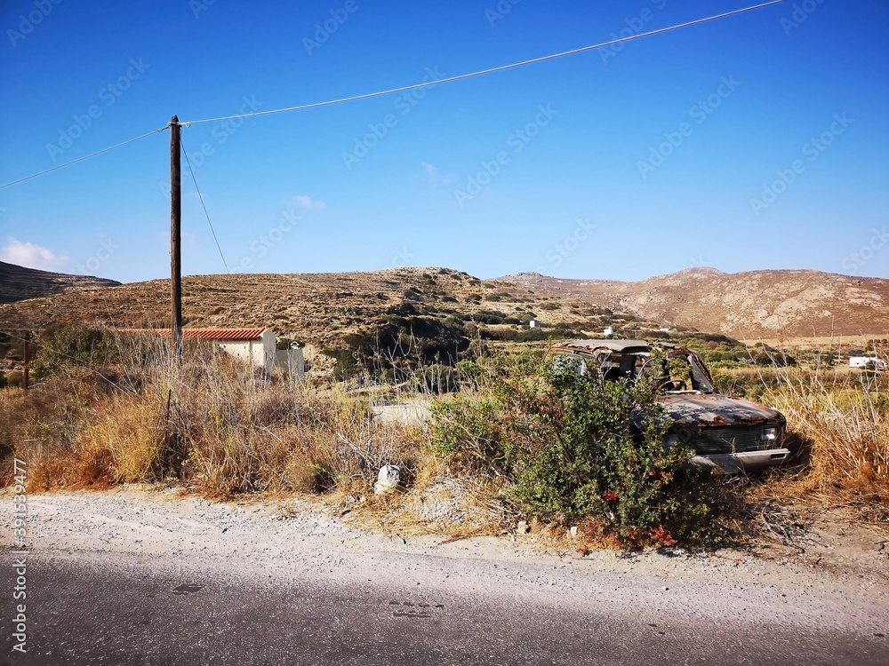 rusty old car before mountain and desert panorama opn the island of Naxos, Greece
