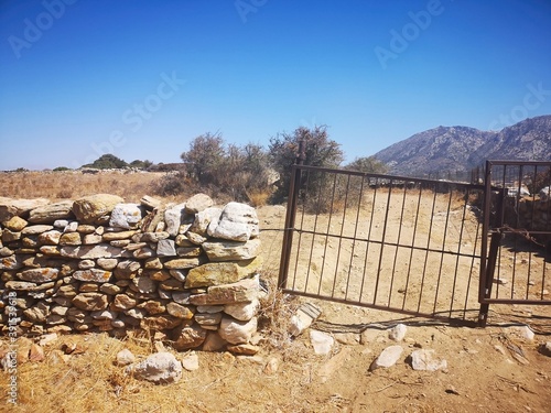 Obraz na płótnie rusty old metal gate and stone wall on the island of Naxos, Greece w salonie