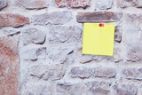Yellow sticky note attached with buttons to the wall
