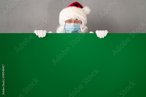 Senior man wearing Santa Claus costume and protective mask