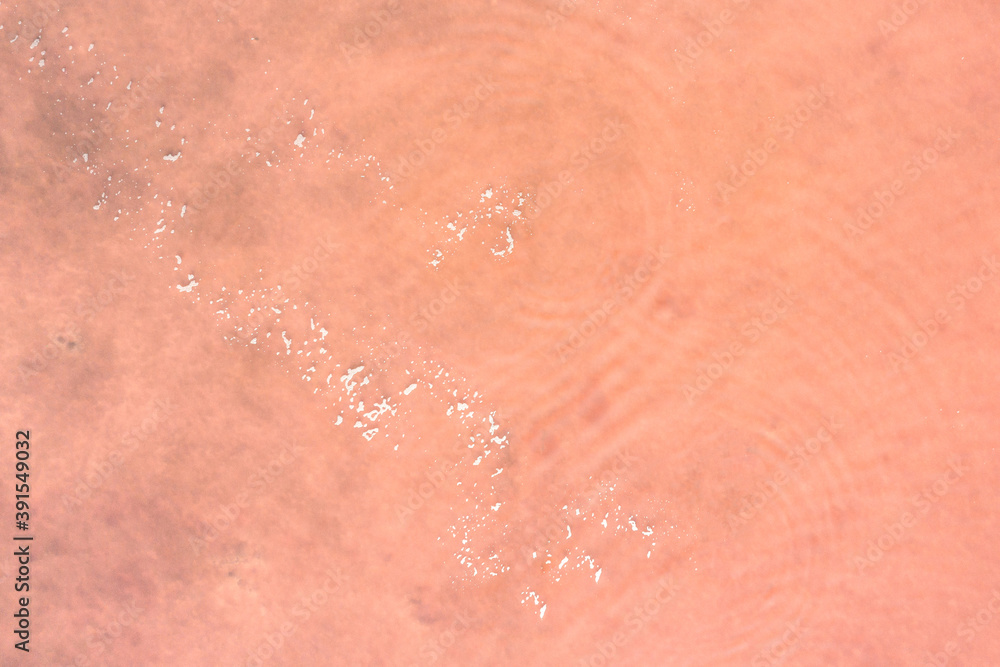 The natural surface of the salty pond is pale pink with a white path of will. Shooting from the air. Copy space. The natural surface of the salty pond is pale pink with a white path of will. Shooting from the air. Copy space.