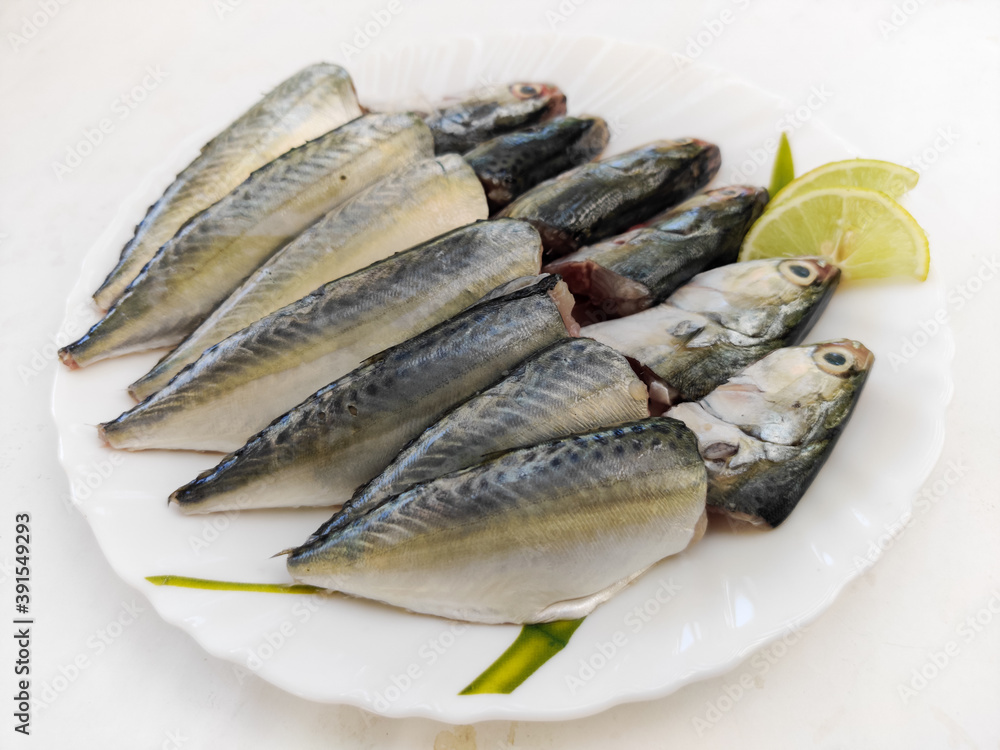 Cleaned and Ready to cook Fresh Fish Horse / Indian Mackerel Fish Decorated with herbs and Vegetables on a white plate. Cleaned and Ready to cook Fresh Fish Horse / Indian Mackerel Fish Decorated with herbs and Vegetables on a white plate.