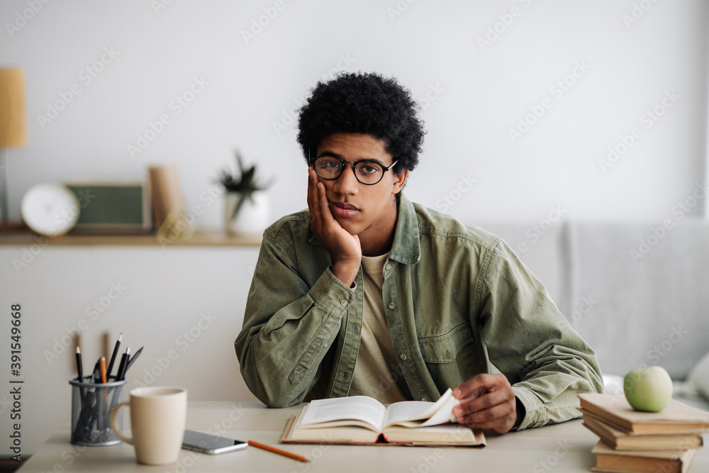 Distance education concept. Bored African American student with textbook studying at home Distance education concept. Bored African American student with textbook studying at home