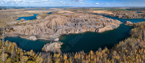 Fancy and unusual autumn aerial landscape of Romantsev mountains wih blue lakes, yellow trees and mud erosion looks like alien surface of Mars. Russia. Tula national park