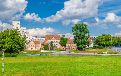 Traeckaje Suburb with old buildings in Trinity Hill district and grass lawn with green trees in Minsk city Nemiga historical centre, blue sky white clouds in sunny summer day, Republic of Belarus © Aliaksandr