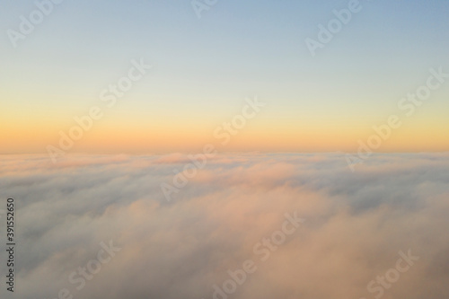 Aerial view gold sunrise over clouds in blue sky. Aerial top view cloudscape. Texture of clouds. View from above. Orange sunrise or sunset over clouds. Panorama clouds texture © Aleksei