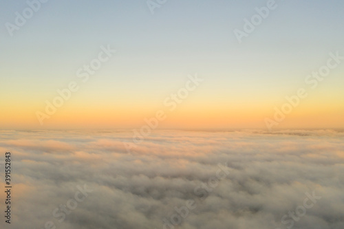 Aerial view gold sunrise over clouds in blue sky. Aerial top view cloudscape. Texture of clouds. View from above. Orange sunrise or sunset over clouds. Panorama clouds texture © Aleksei