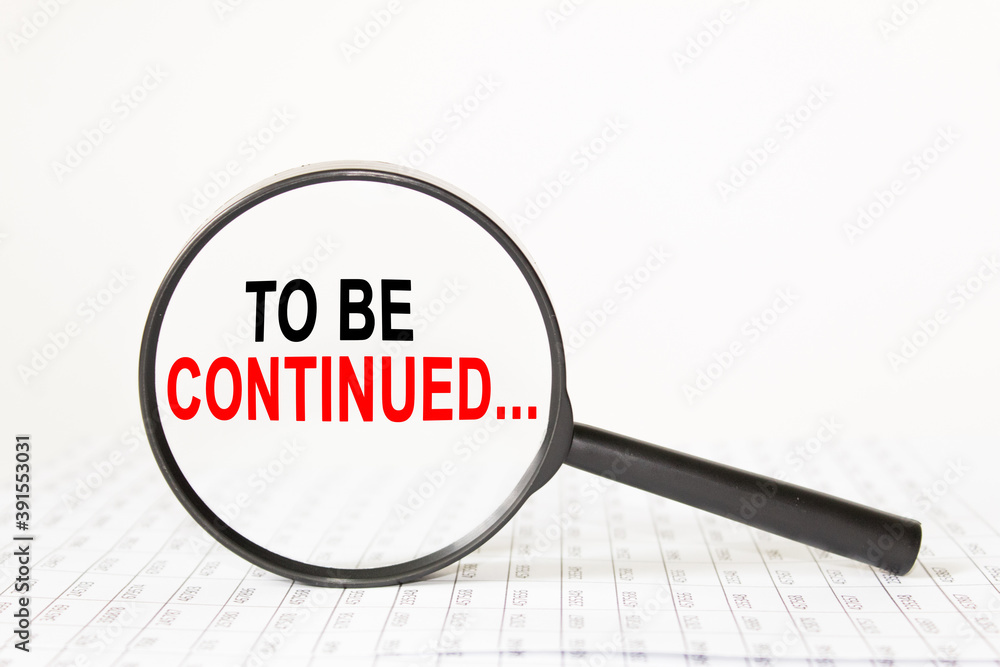 words TO BE CONTINUED in a magnifying glass on a white background. business concept words TO BE CONTINUED in a magnifying glass on a white background. business concept