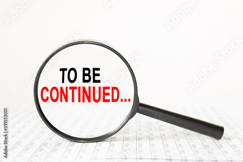 words TO BE CONTINUED in a magnifying glass on a white background. business concept