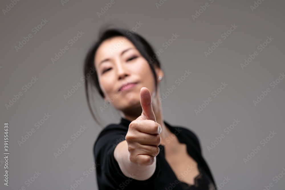 Pleased confident Asian woman giving a thumbs up Pleased confident Asian woman giving a thumbs up