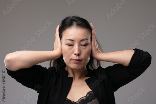 Asian woman holding her hands covering her eyes photo